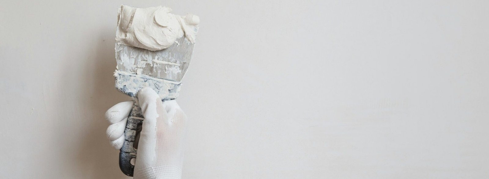 Worker in white gloves performs plastering of the walls of the room